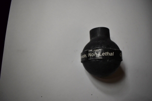 a hand ball rubber black grenade, about softball sized, with white writing that says Grenade non lethal