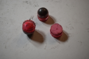 fn303 rounds are pictured, some are intact and some just pieces of broken plastic casings, but horrible bismuth beads are seen up front in the intact balls. They look a lot like pepper balls, round and plastic, two halves snapped together like sinister Easter Eggs, but the have stabilizers on the bottom to direct their impact. Rough plastic with channels for aerodynamic performance.