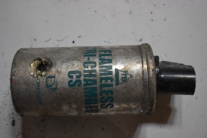 silver grenade can with black top and blue writing that says Flameless Tri-Chamber CS and has a hole in the bottom center, background is white paper with a shadow